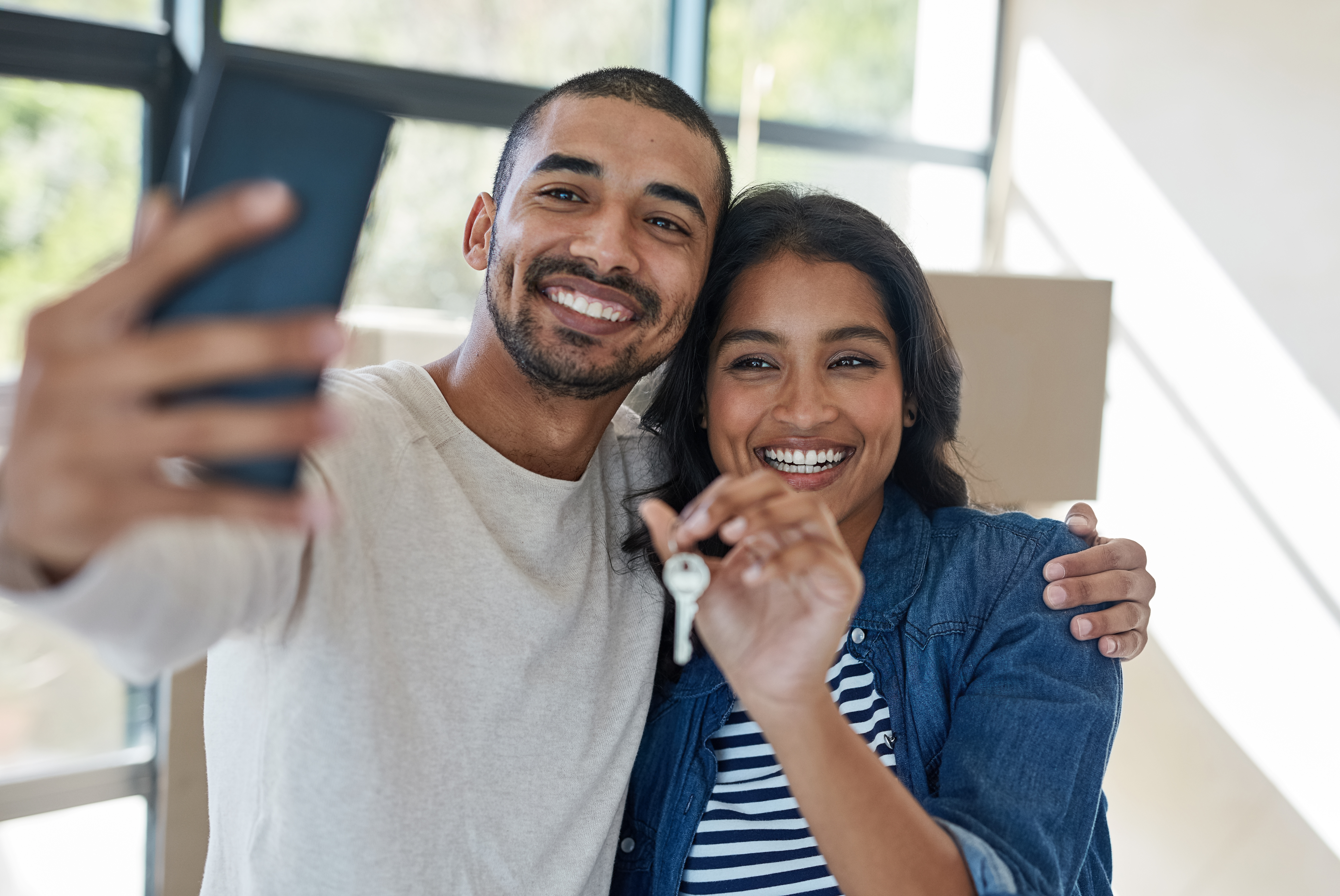 Female holding a house key as man takes selfie