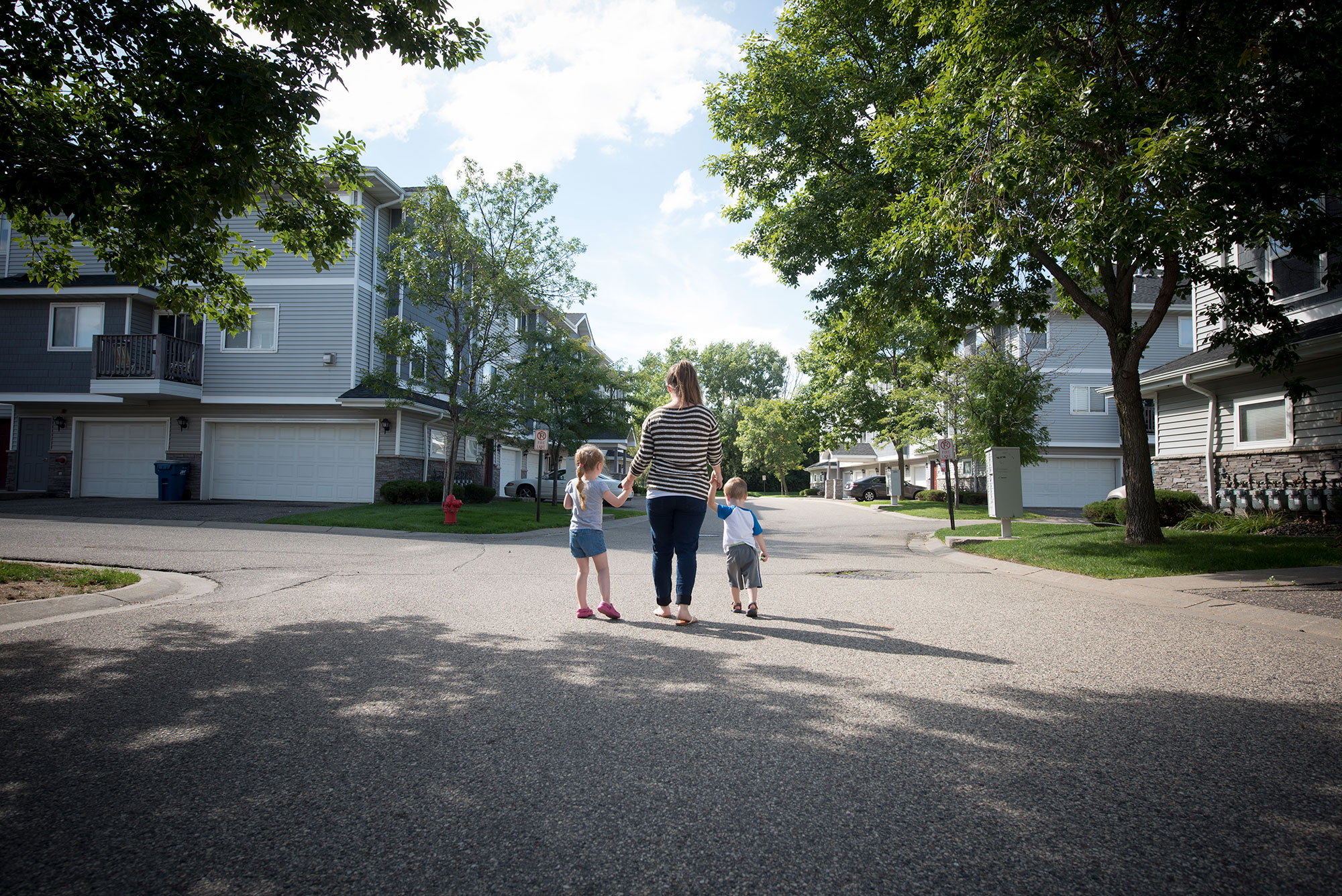 Woman and two kids walking down street